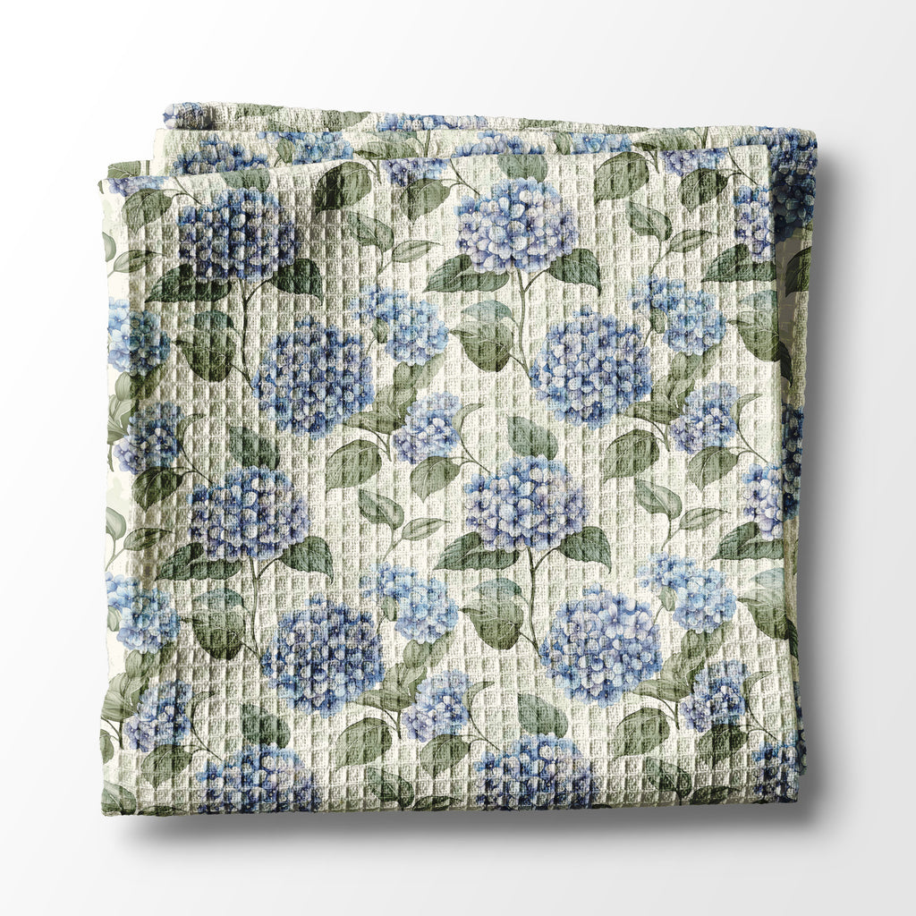 Floral kitchen towel with blue flowers and green leaves on a white background