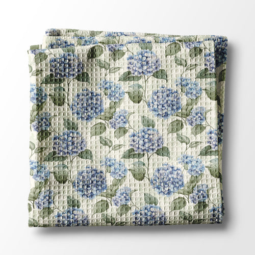 Floral kitchen towel with blue flowers and green leaves on a white background
