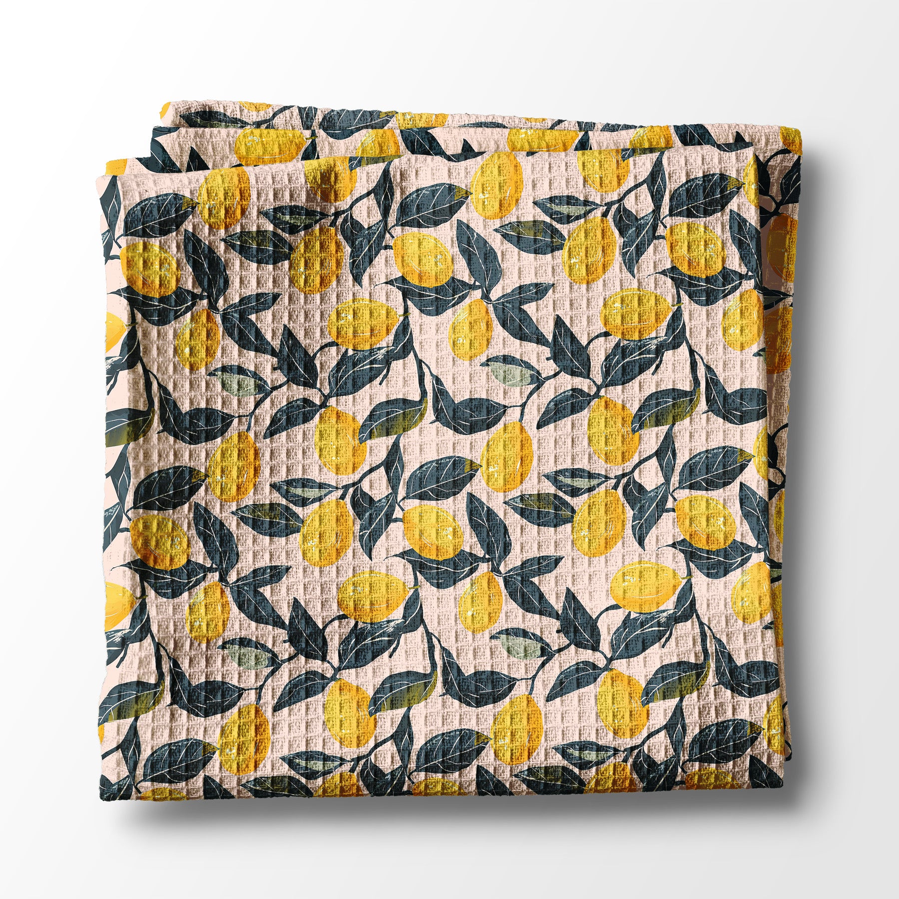 Folded kitchen towel with lemon and leaf pattern on a white background