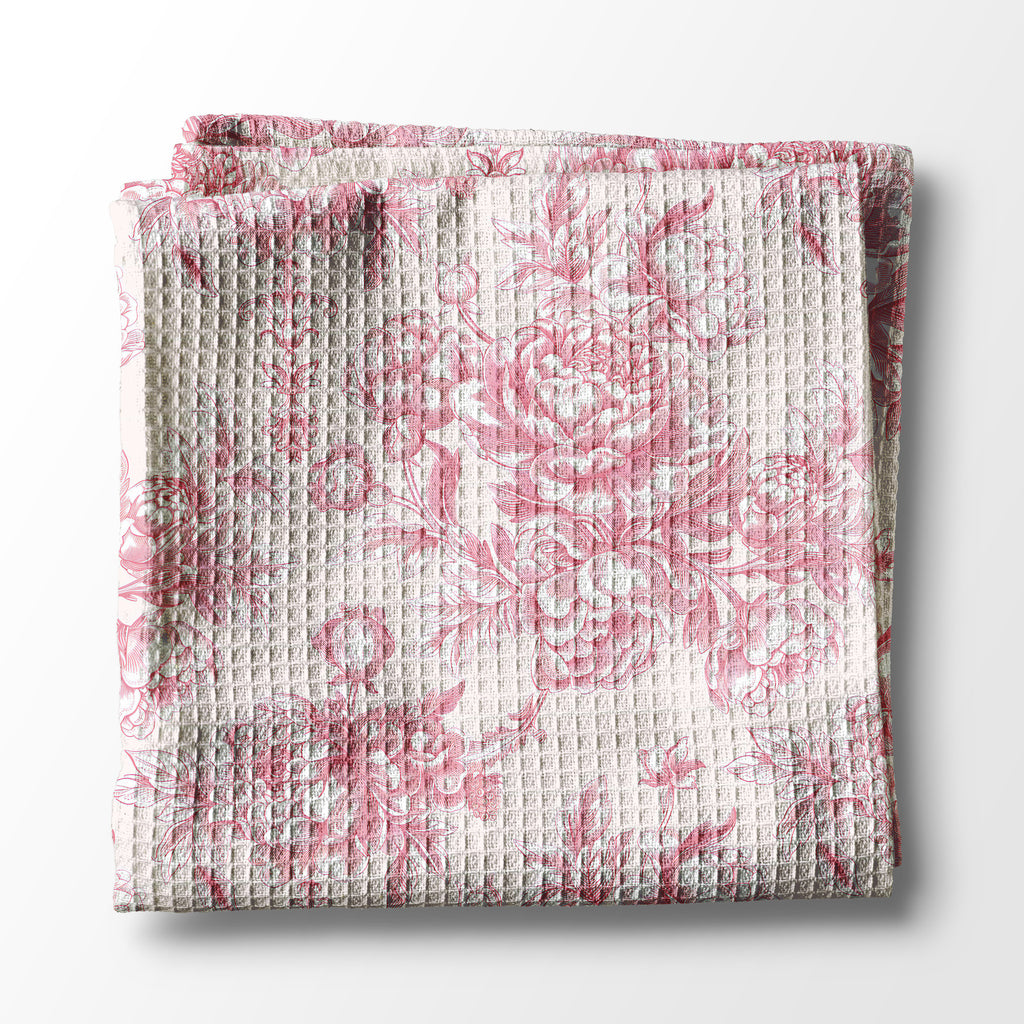 Folded kitchen towel with pink floral pattern on a white background