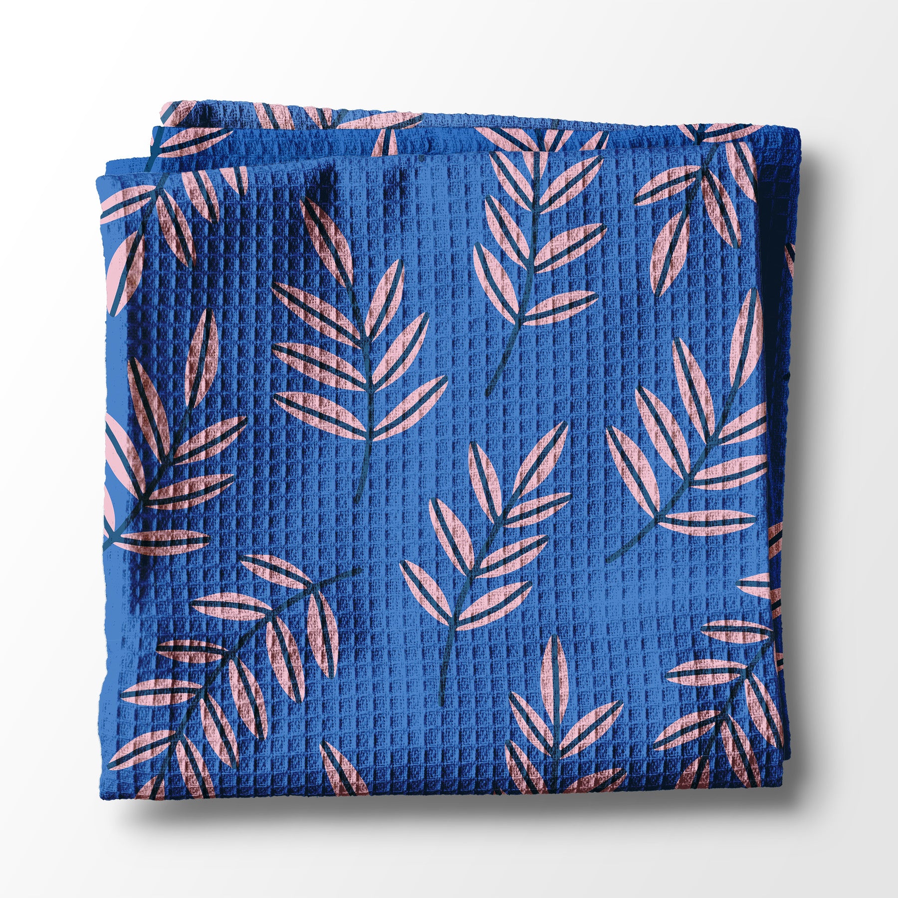 Folded blue kitchen towel with pink leaf pattern on a white background