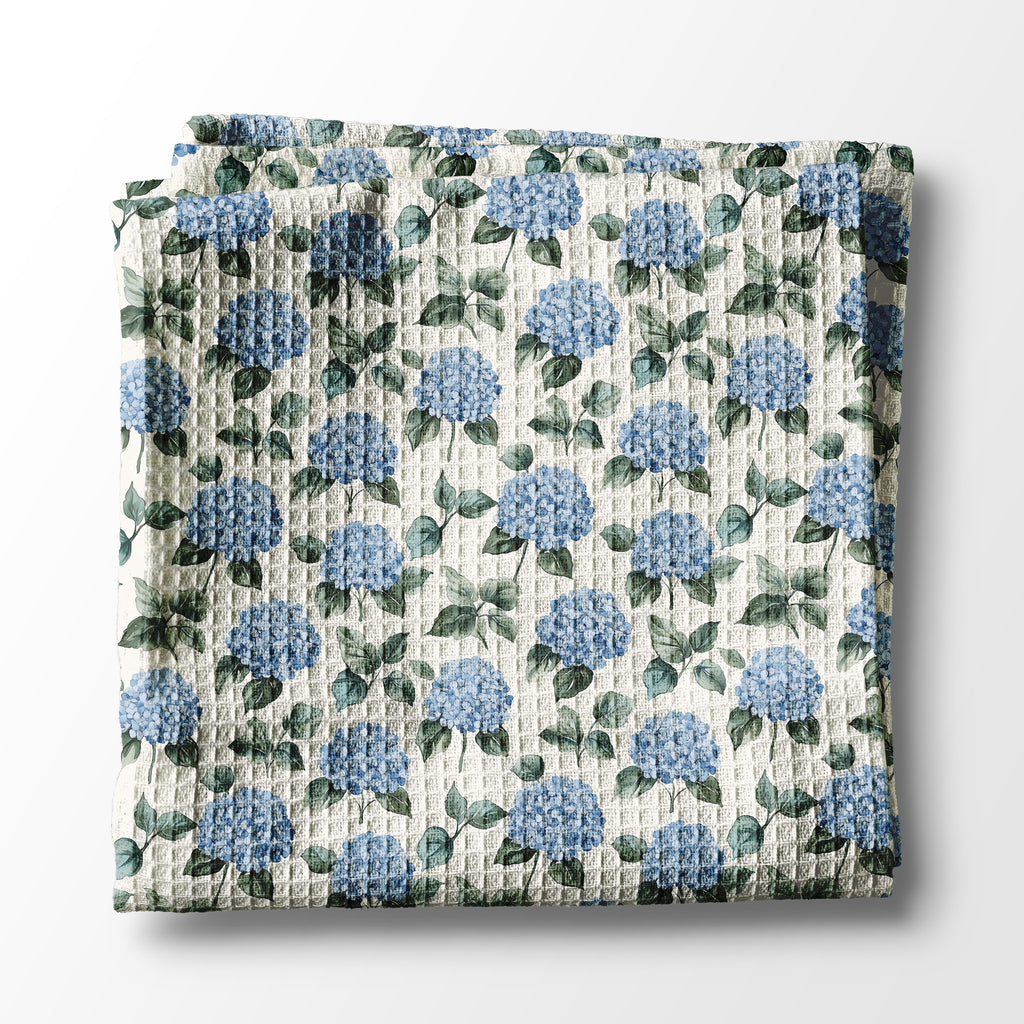 Floral patterned kitchen towel with blue flowers and green leaves on a white background