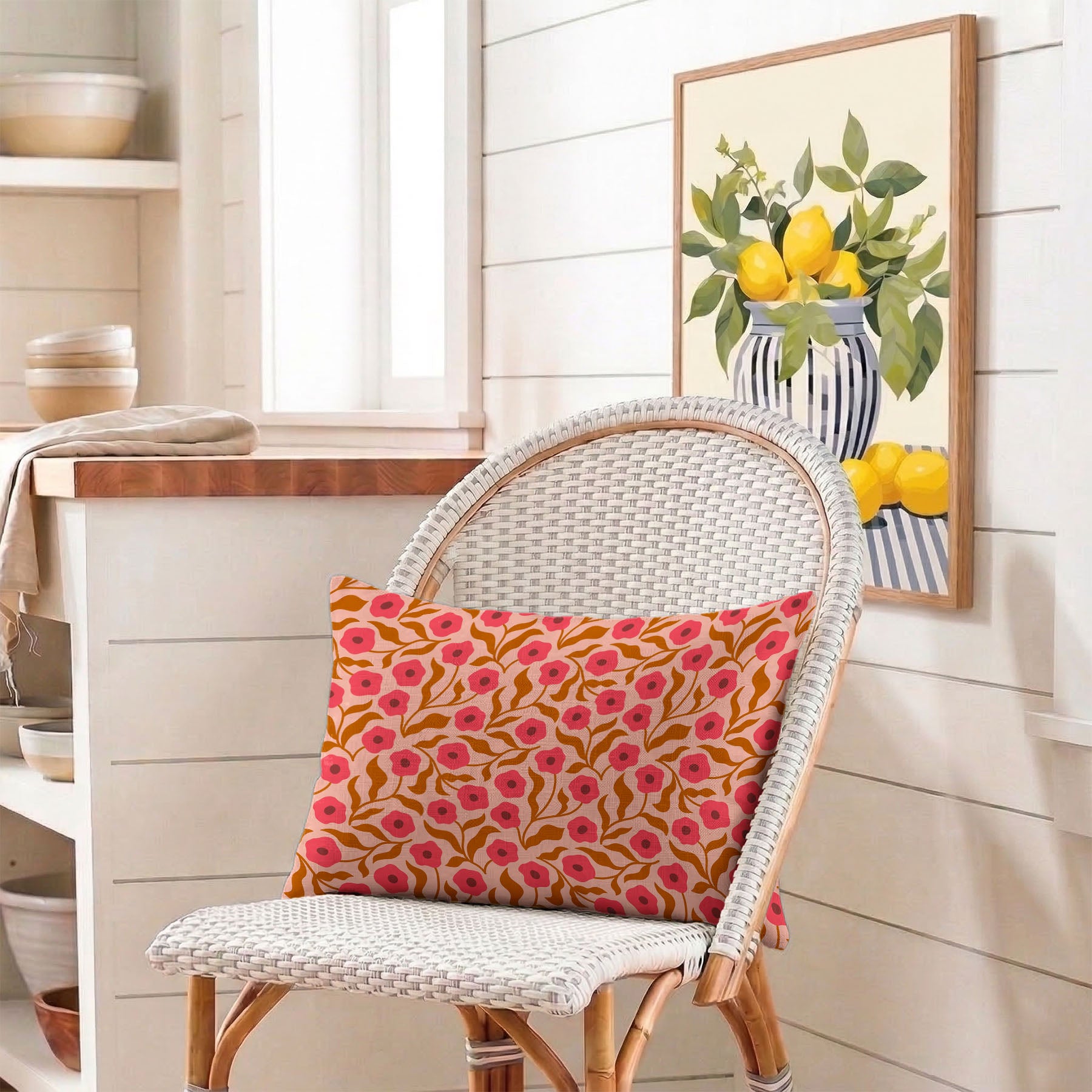 Wicker chair with a Poppy pattern lumbar pillow in a room with a framed picture of lemons on the wall.