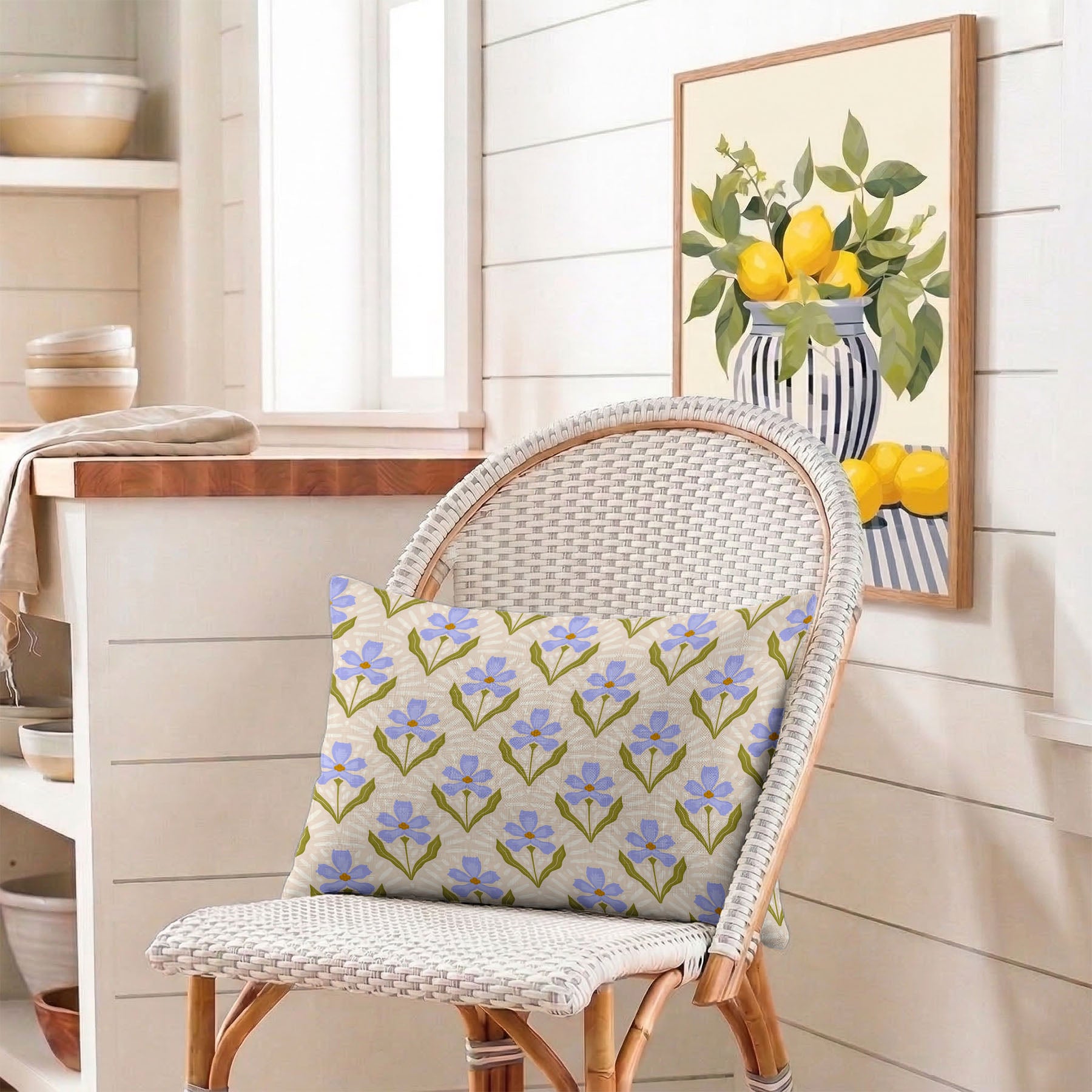 Wicker chair with a Sweet Floral lumbar pillow in a room with a framed picture of lemons on the wall.