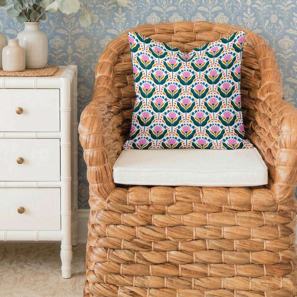 Square decorative pillow with Piper pattern on a wicker chair against a wallpapered wall.