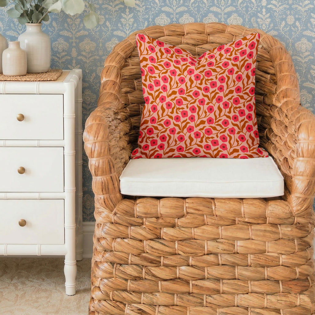Wicker chair with a Poppy pattern pillow in a room with decorative wallpaper and furniture.