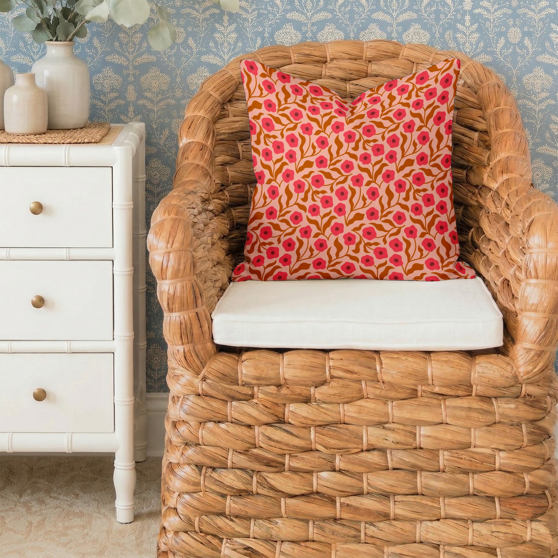 Wicker chair with a Poppy pattern pillow in a room with decorative wallpaper and furniture.