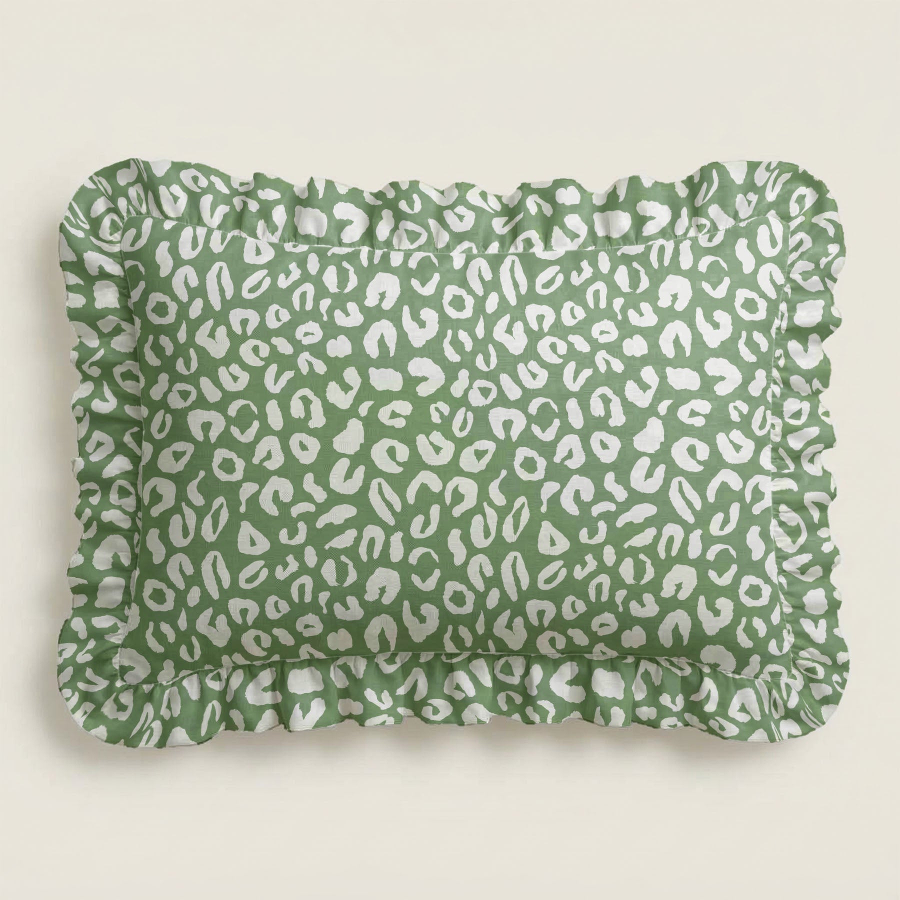 Green pillow with white leopard print pattern on a light beige background