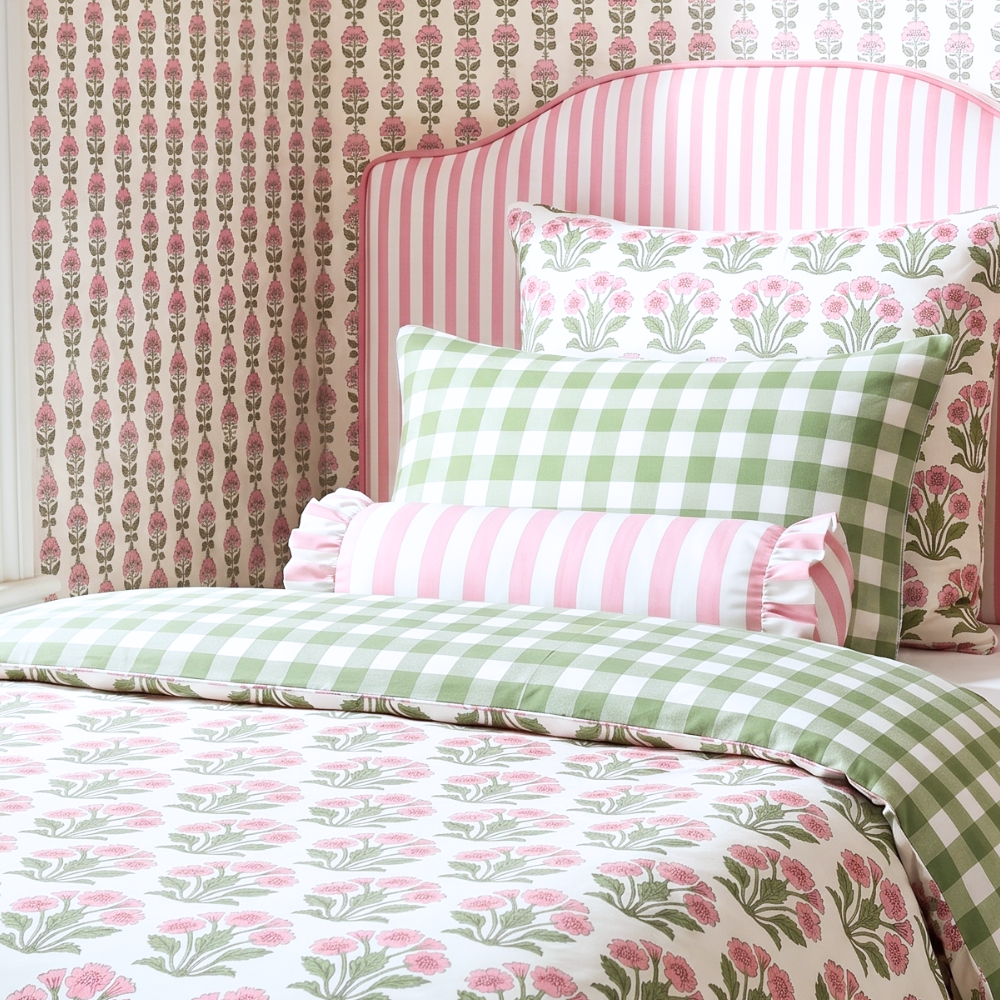 Bed with floral and checkered bedding against a patterned wall.