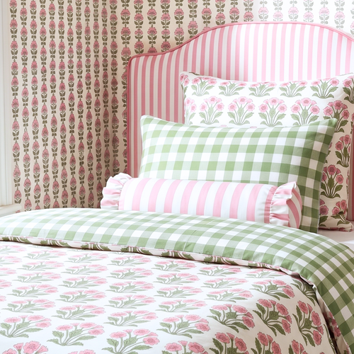 Bed with floral and checkered bedding against a patterned wall.