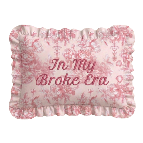 Decorative pillow with floral pattern and text 'In My Broke Era' on a white background