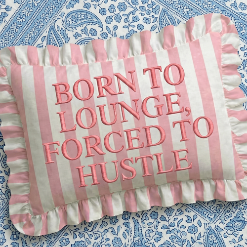 Striped pillow with pink text on a blue patterned background